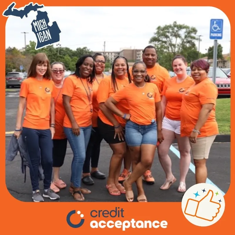 Photo booth snapshot of a team in orange shirts on a Credit Acceptance Michigan frame