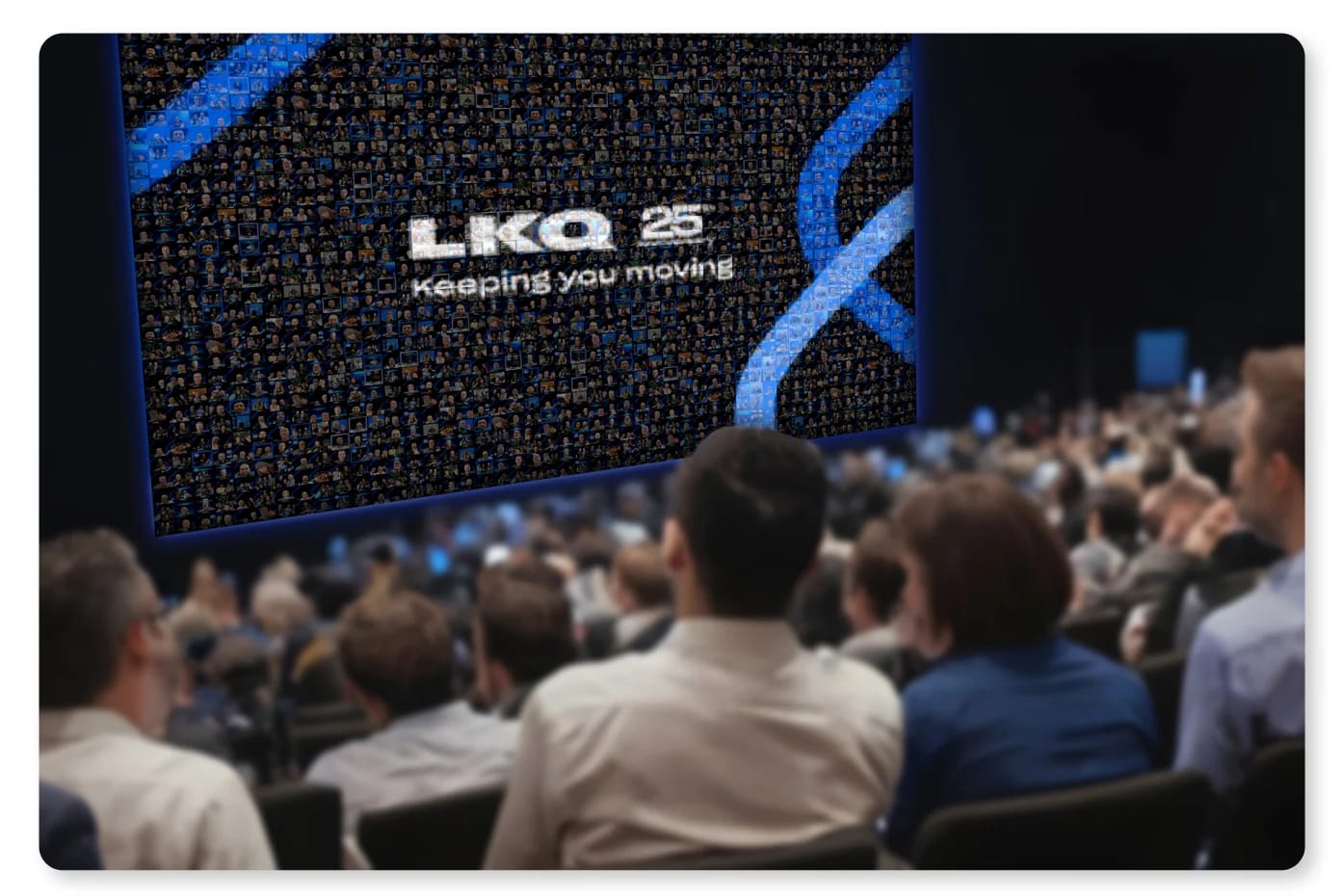 A conference audience watching a live photo mosaic of their own headshots assemble on a stage-width screen.