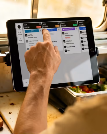 Hand interacting with a Fresh KDS screen displaying a restaurant order management system.
