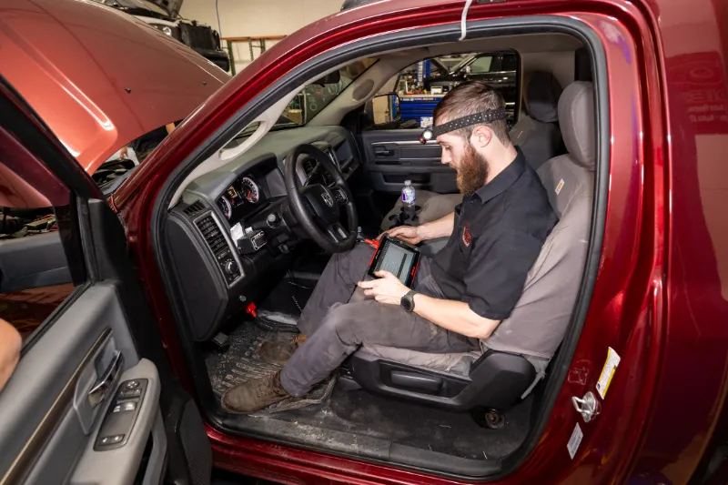 Technician performing diagnostic scan inside a heavy-duty truck using an electronic tablet tool.