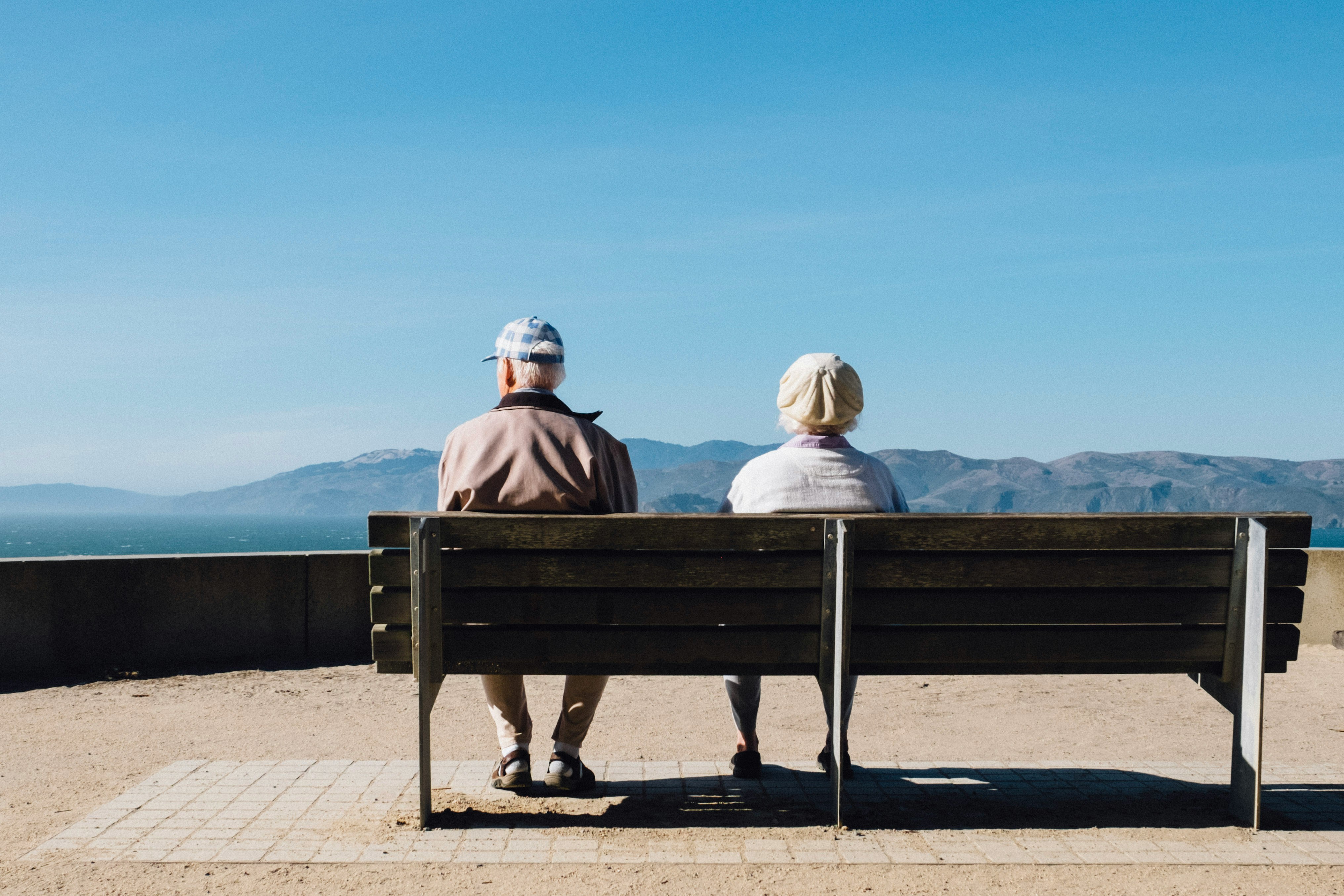 Photo of an elderly couple sitting on a bench overlooking water