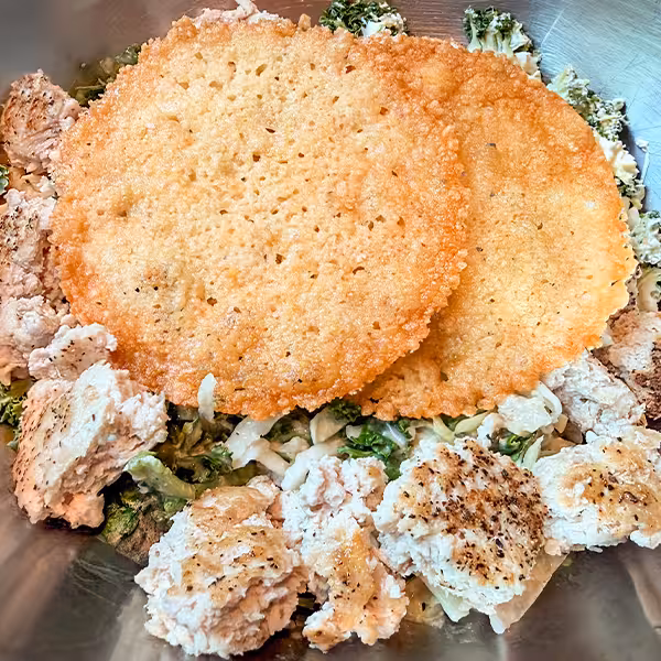 Packed with protein (52g) & fiber this bowl features house greens tossed in creamy caesar dressing, topped with diced ground chicken patty, grated parmesan & parmesan cheese crisps