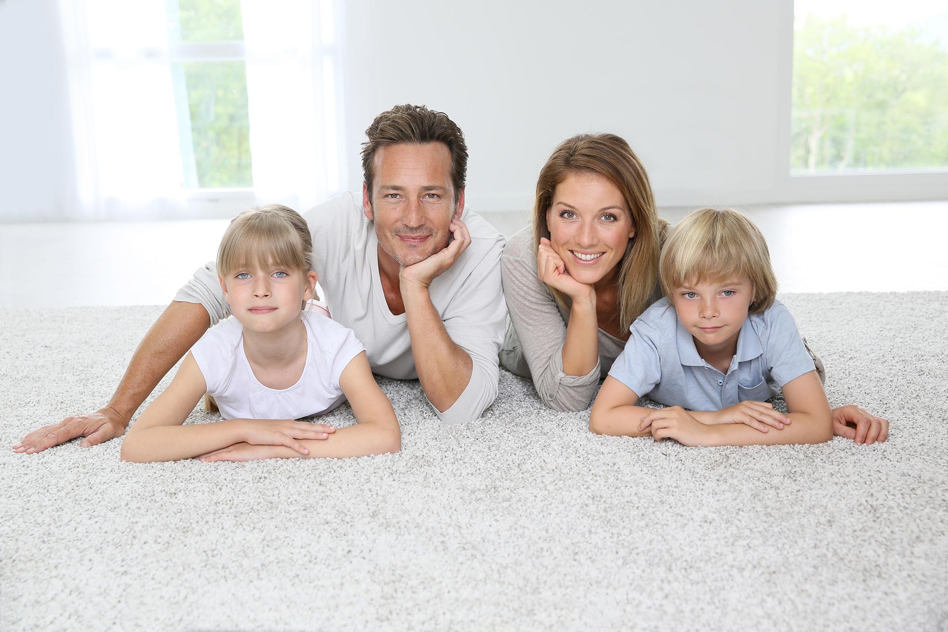 A family laying on a clean white carpet