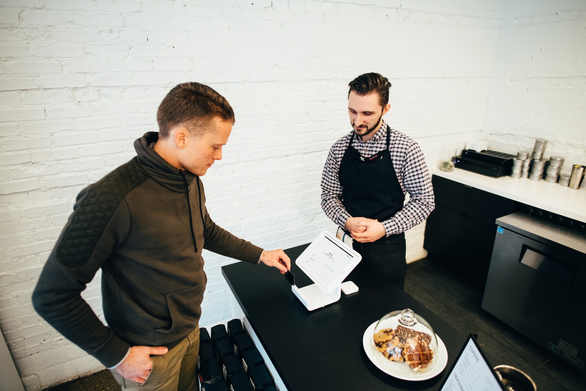 A cafe customer paying with a card on a POS system
