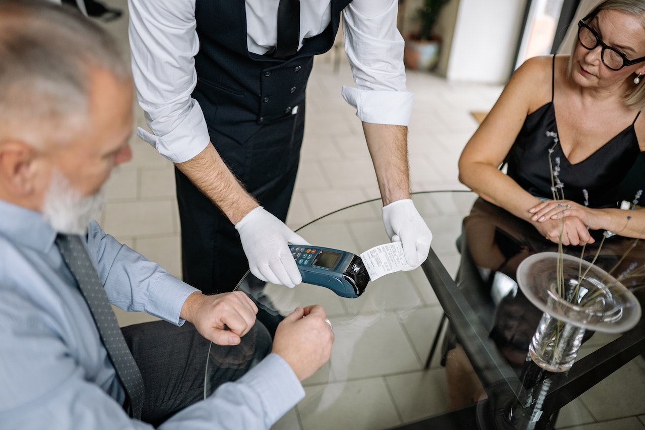 Two restaurant customers paying at the table through a POS card terminal