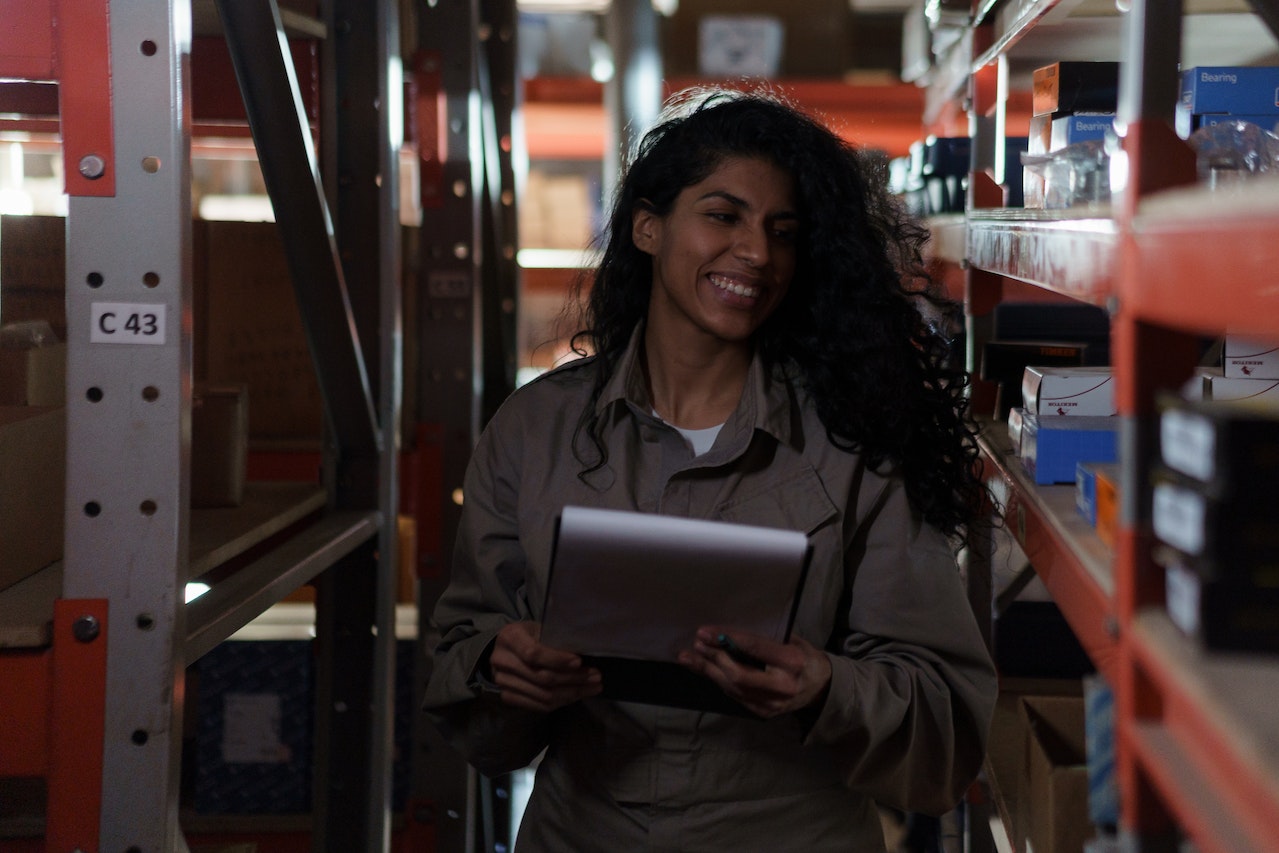A woman checking inventory while smiling and holding a clipboard
