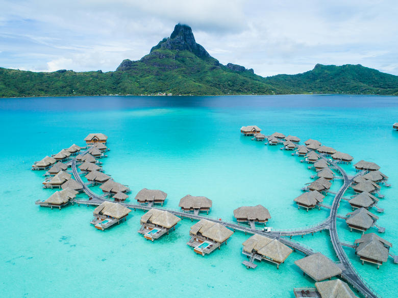 Aerial view of overwater bungalows at the Intercontinental Bora Bora & Thalasso Spa with Mt. Otemanu in the distance.
