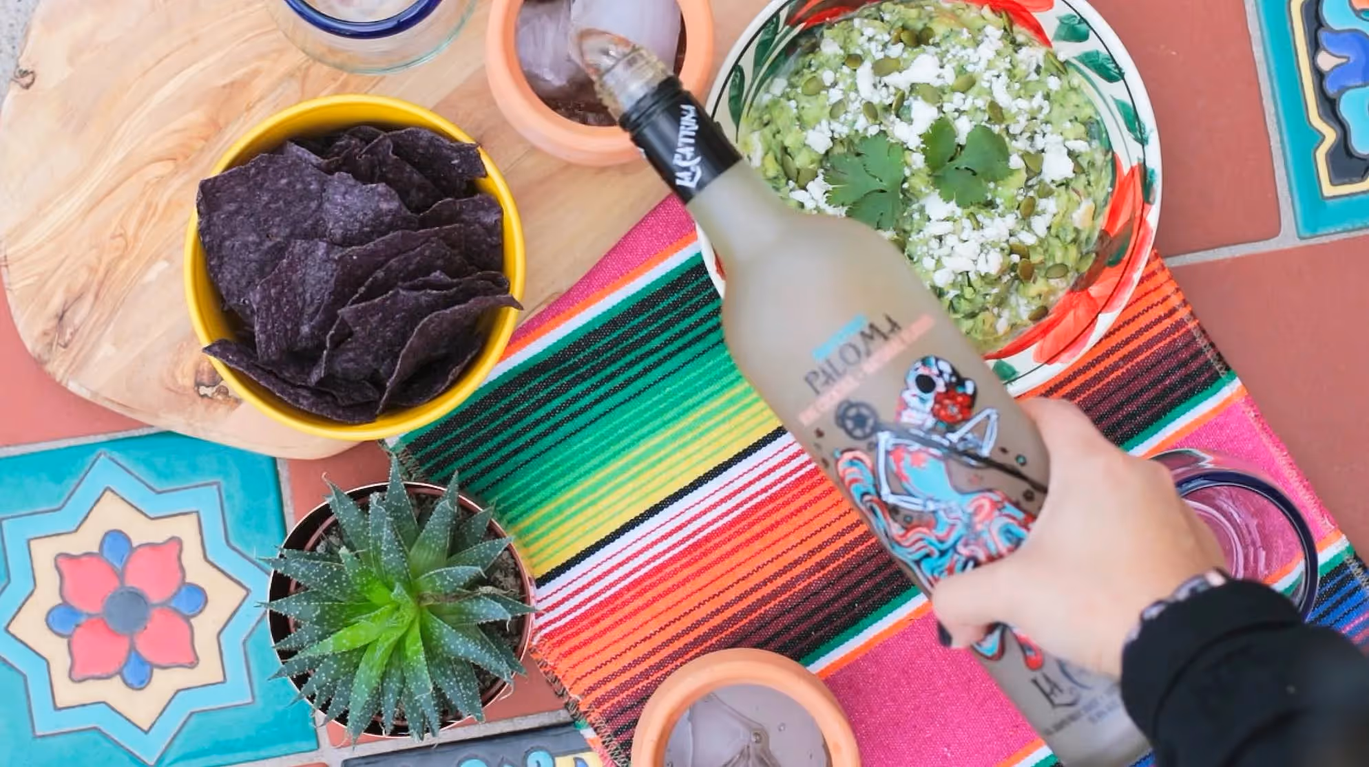 A bottle of La Catrina Ready-to-Drink Paloma being poured into a cup on a festive table