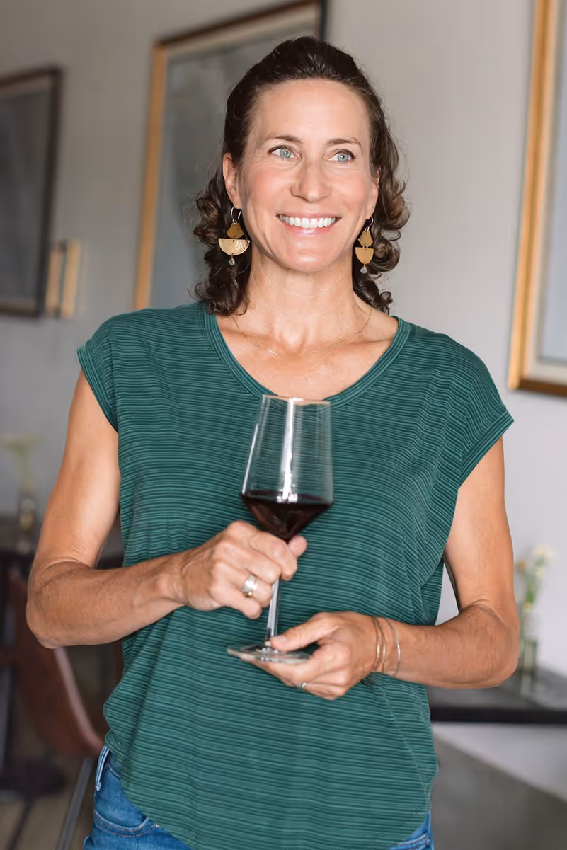 skyfall winemaker nicole walsh poses for camera while holding a glass of red wine in the tasting room