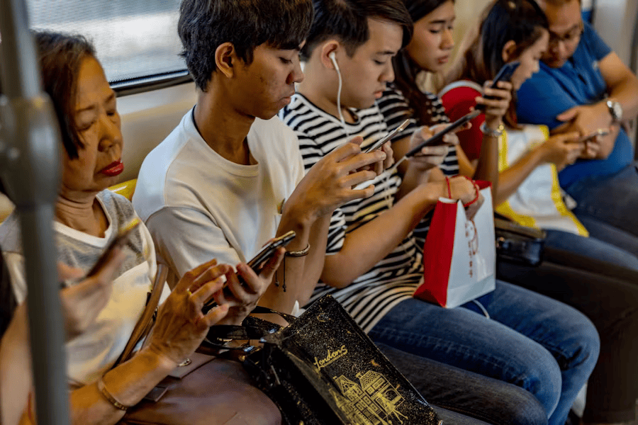 Menschen sitzen in der Bahn, ohne ein Wort zu sprechen, sind alle am Handy, was die Suchtgefahr von social media zeigt.