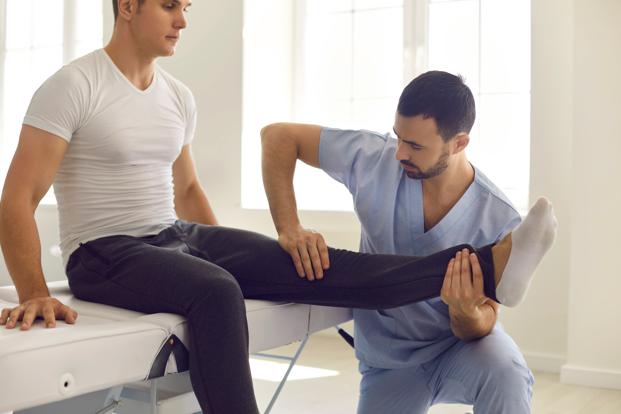 Physiotherapeut behandelt Bein eines Patienten
