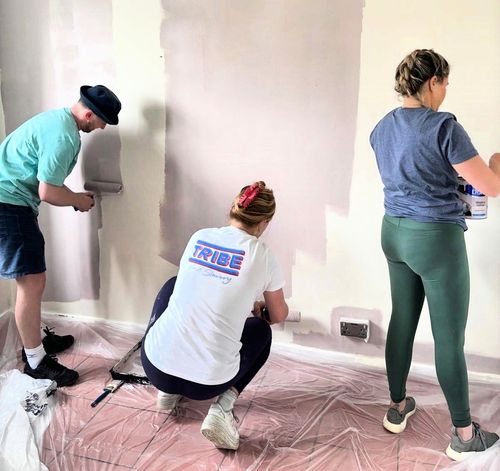 A picture for three volunteers painting a room in a property purchases by Ella's charity, a project funded by Quaker Housing Trust