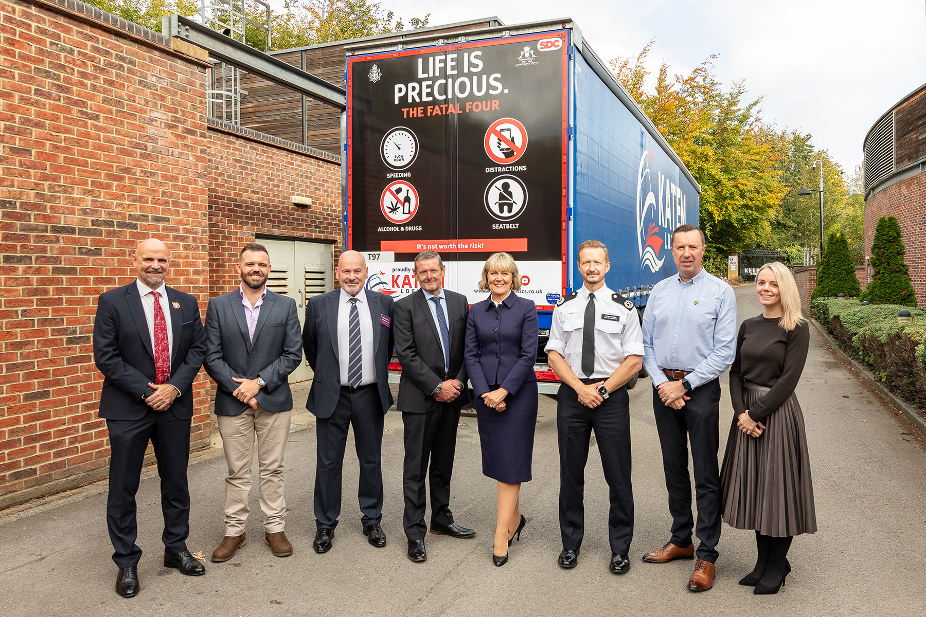 Group of people standing in front of an HGV wagon with 'Life is Precious' slogan