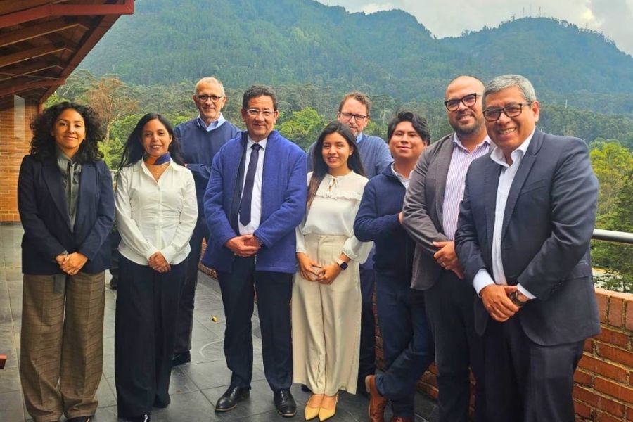 Grupo de representantes universitarios posa en una terraza durante una visita institucional en Bogotá, con un paisaje montañoso al fondo. Están vestidos de manera formal y semiformal, en un ambiente de encuentro académico y colaboración.