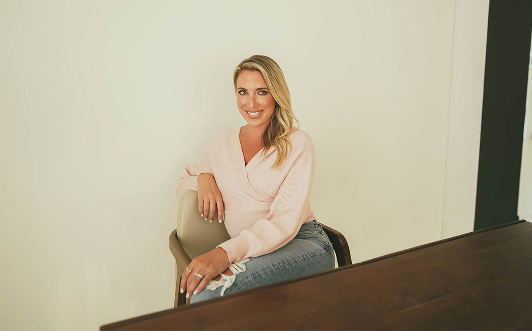 woman in pink shirt sitting at table smiling