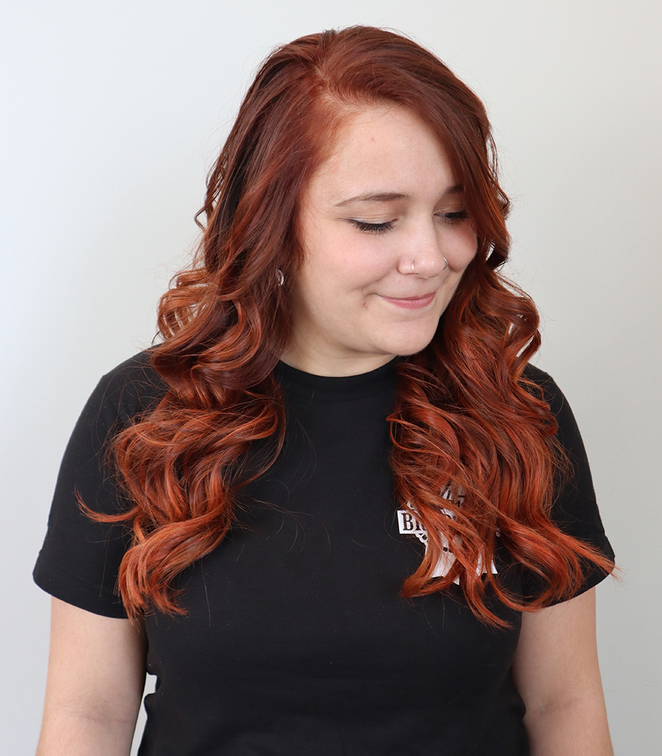 Smiling hair salon client with long auburn hair.