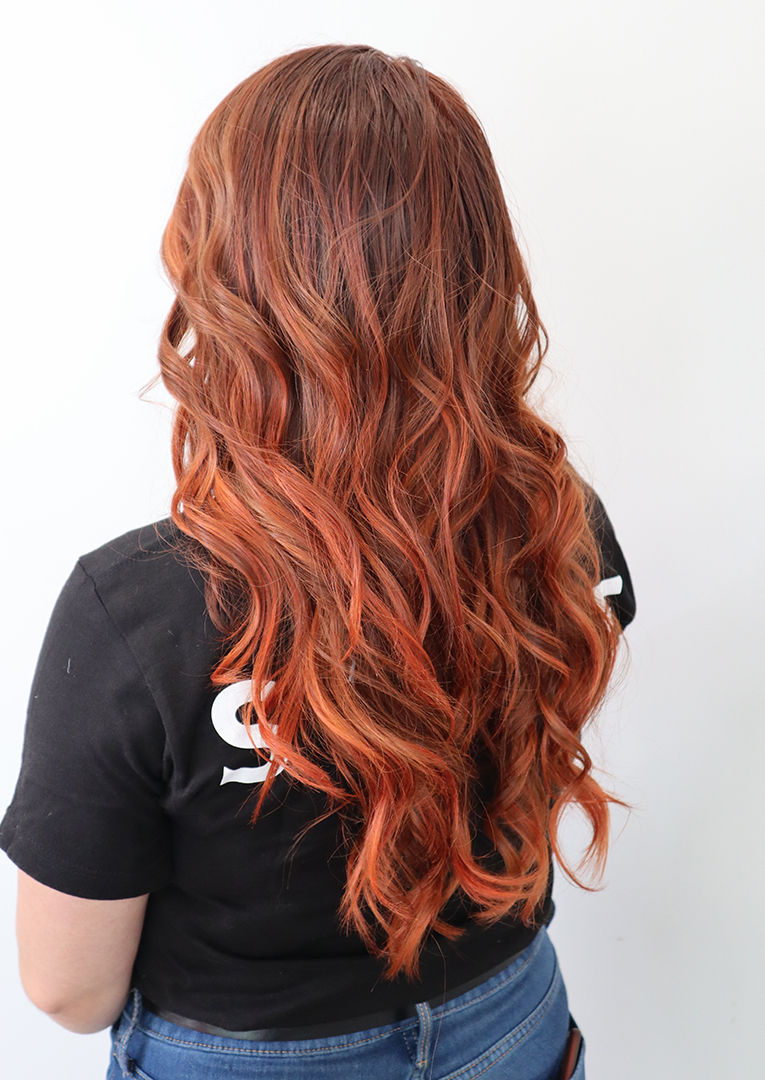 Hair salon client with long auburn hair from the back