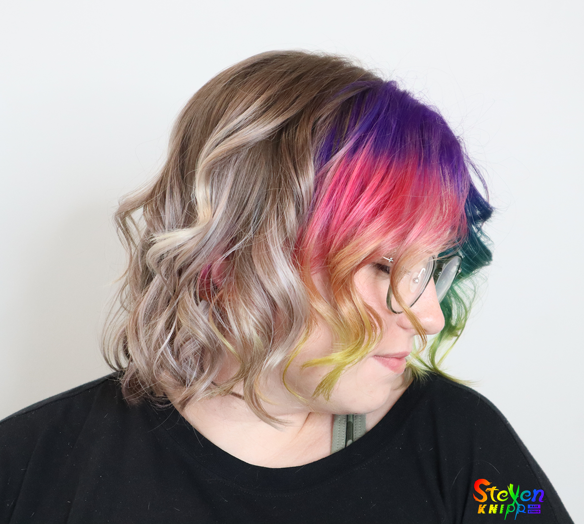 Smiling hair salon client with blonde hair, with a rainbow colored piece in front