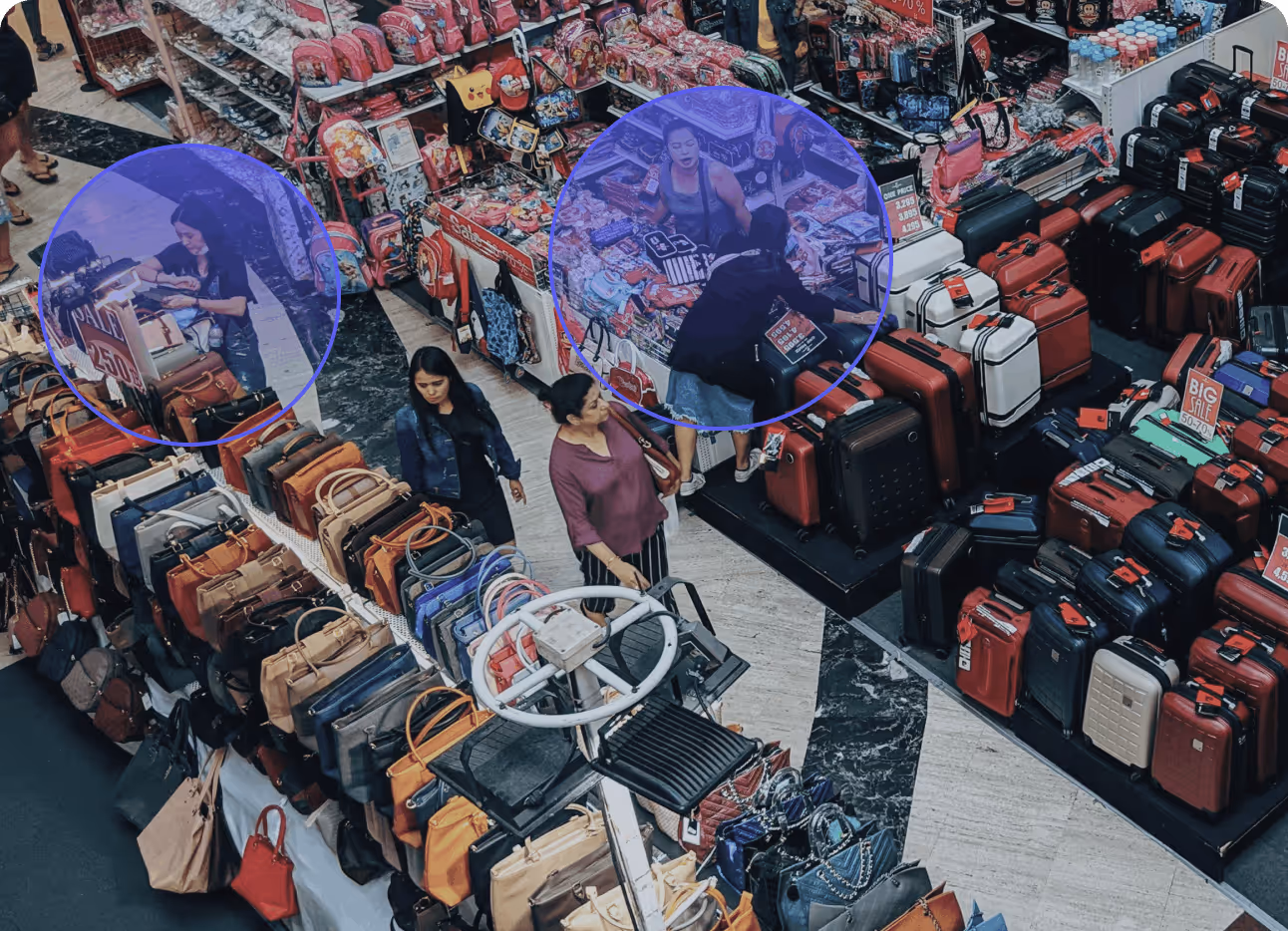 Shoppers browse handbags and luggage on sale in a crowded retail market stall area.