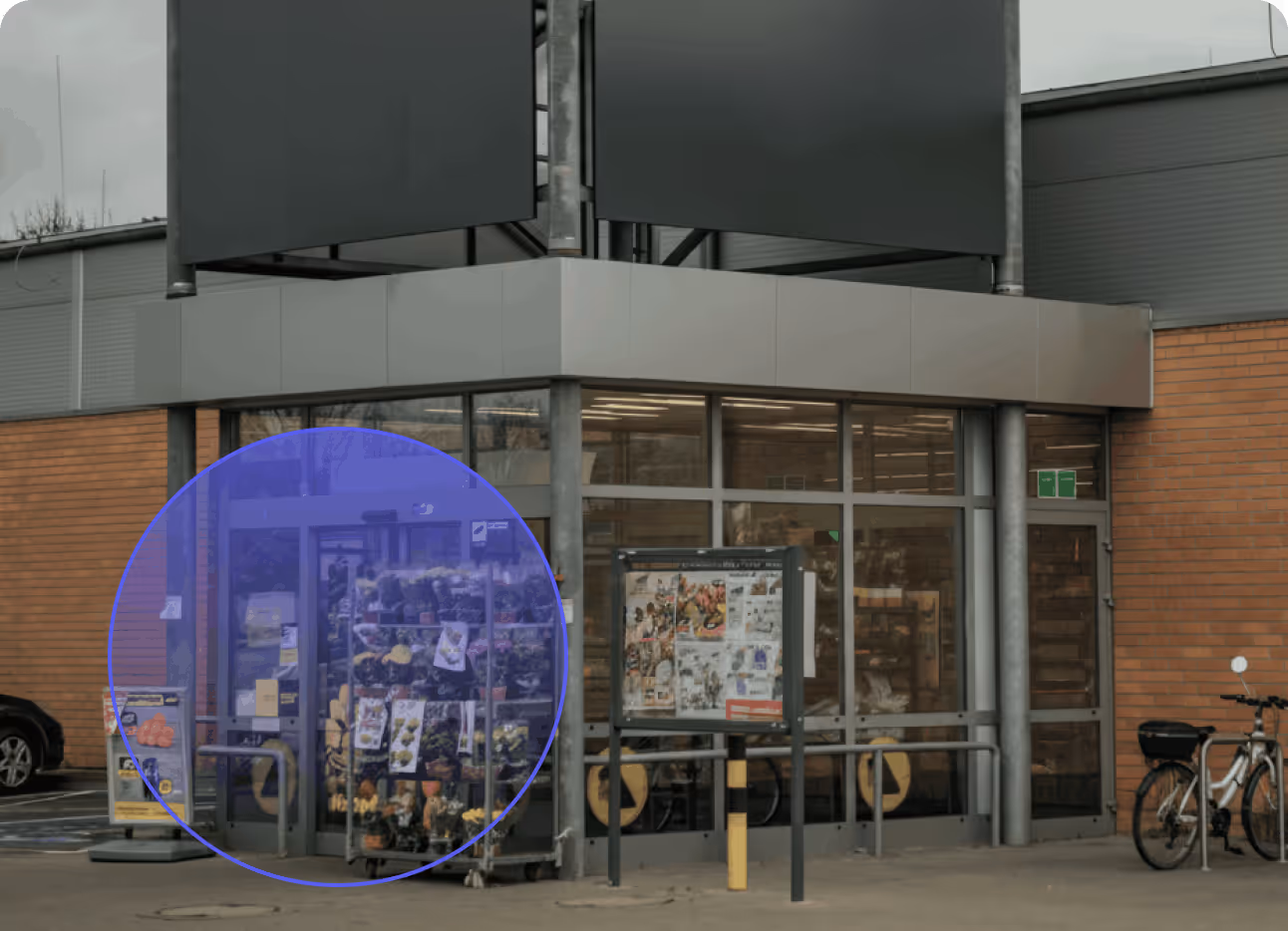 Store entrance with glass doors, flower display stand, and a bicycle parked nearby.