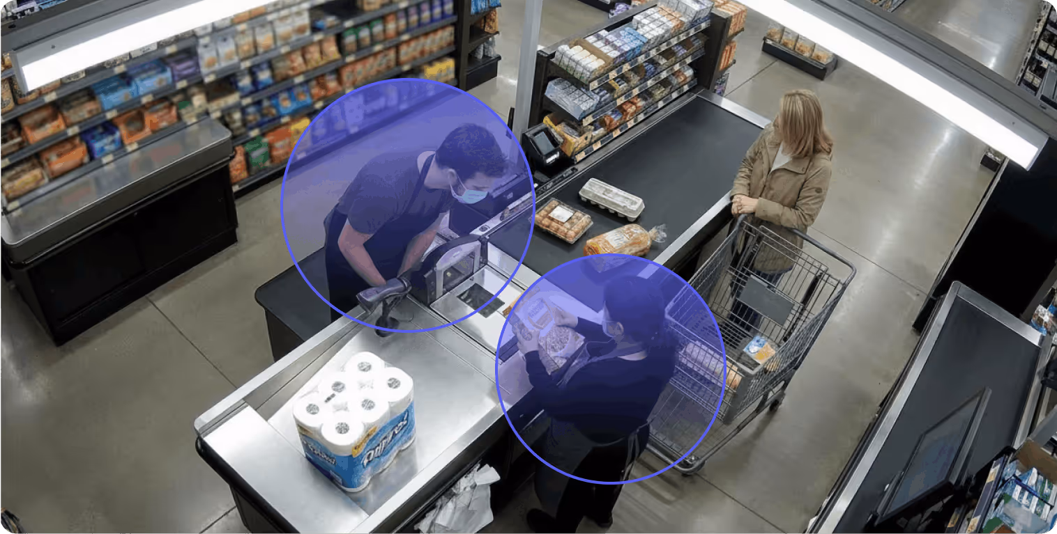 Masked cashier scanning groceries for a customer with a cart at a supermarket checkout.