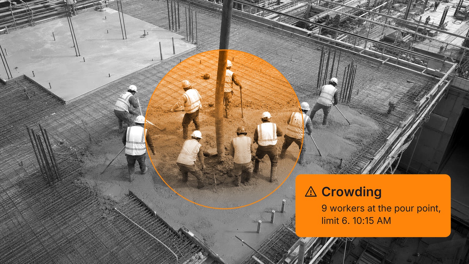 Nine construction workers in hard hats and hi-vis vests, seen from above and behind, crowd around the end of a concrete pump hose, raking and vibrating fresh concrete on the rebar deck of a building under construction, in black and white with a Spot AI detection overlay.