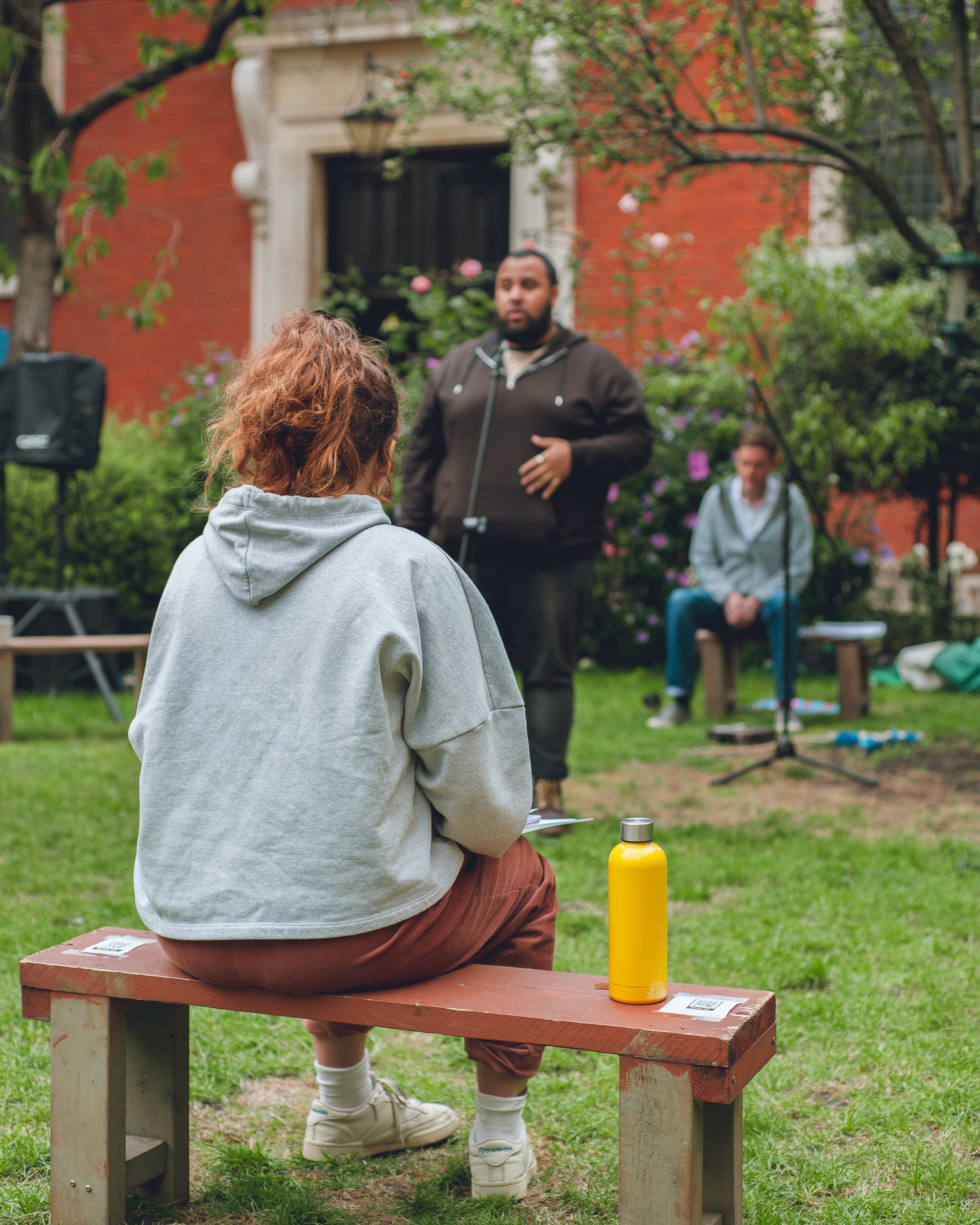 A man talking to a group of people in a concert in a park.