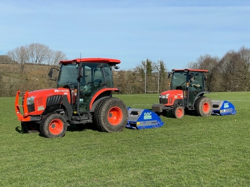 Two tractors with shockwave aerators on a rugby pitch