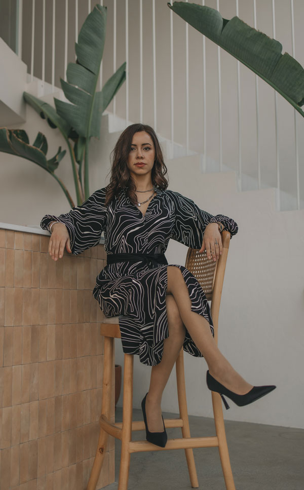 Karina sitting poised on a stool looking confident