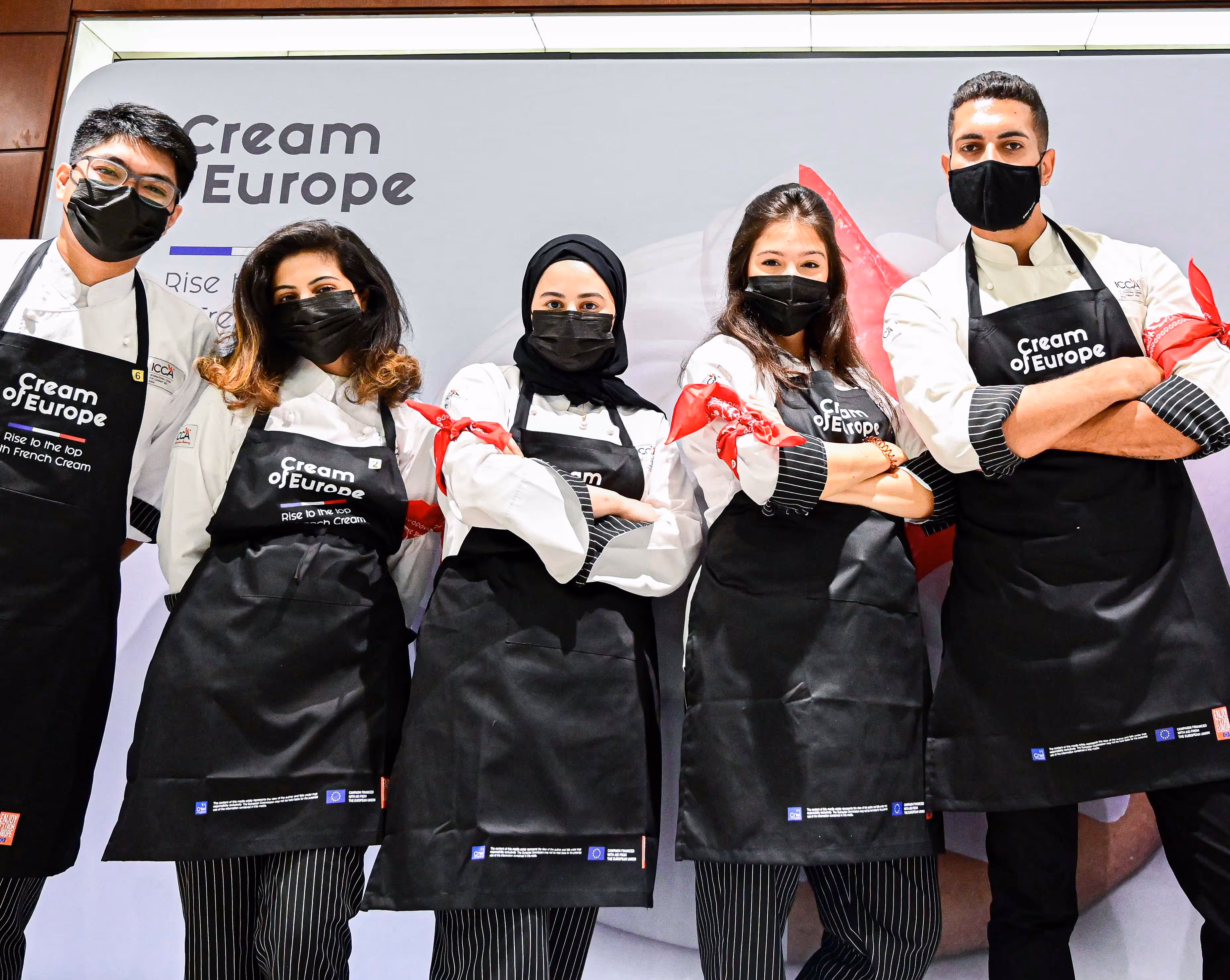 A group of people standing next to each other wearing black aprons.