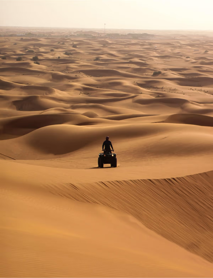 A person riding a four - wheeler in the desert.