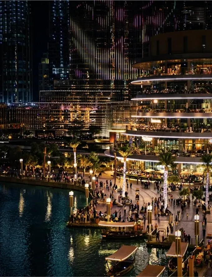 A group of people standing around a marina at night.