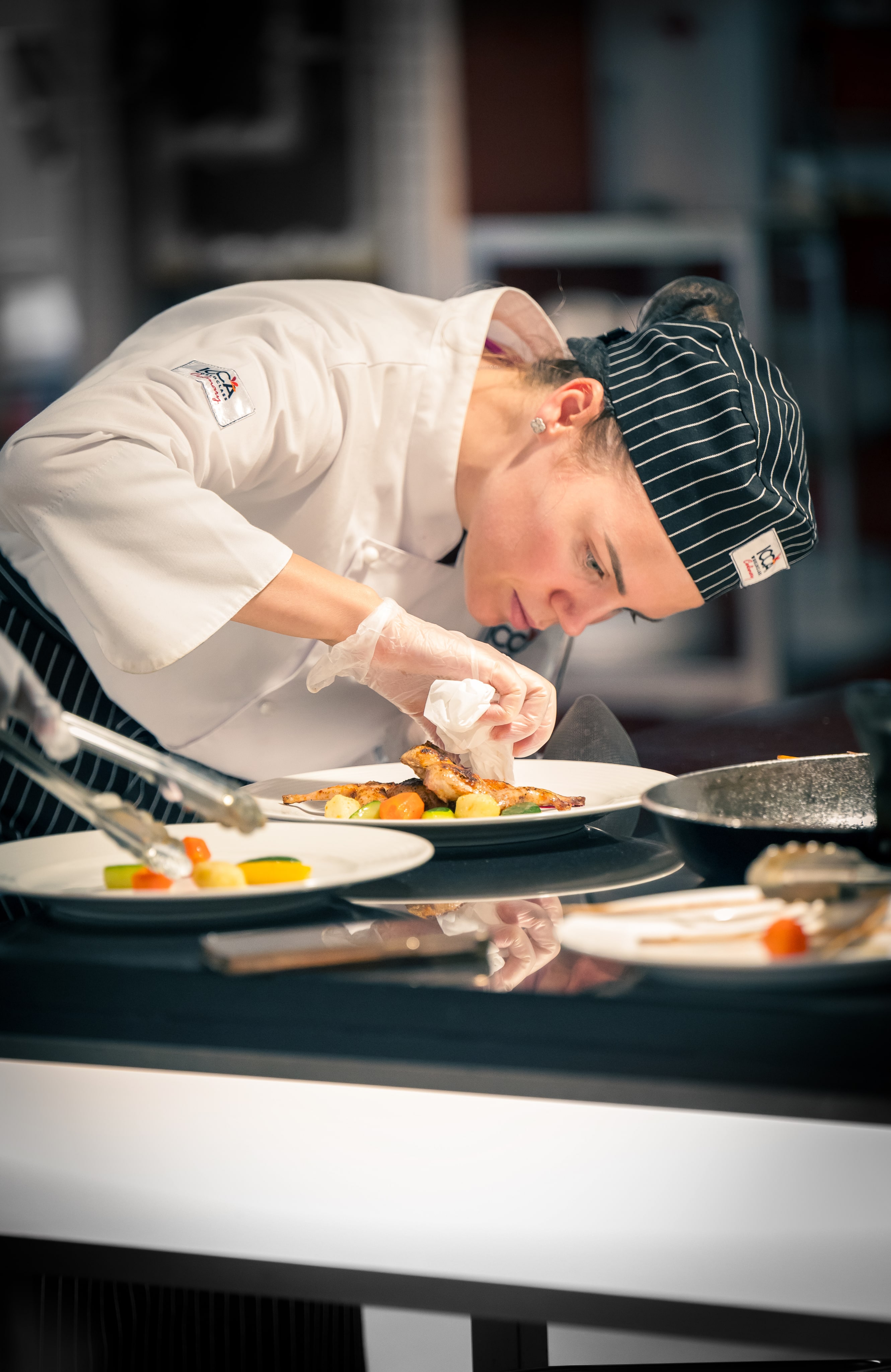 A chef preparing food on a plate in a kitchen.
