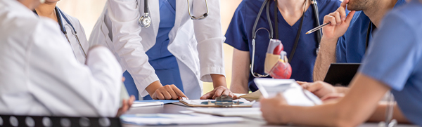 A group of doctors and nurses around a table looking at clipboards