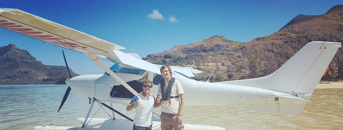 Pessoas posando para foto em frente a um avião