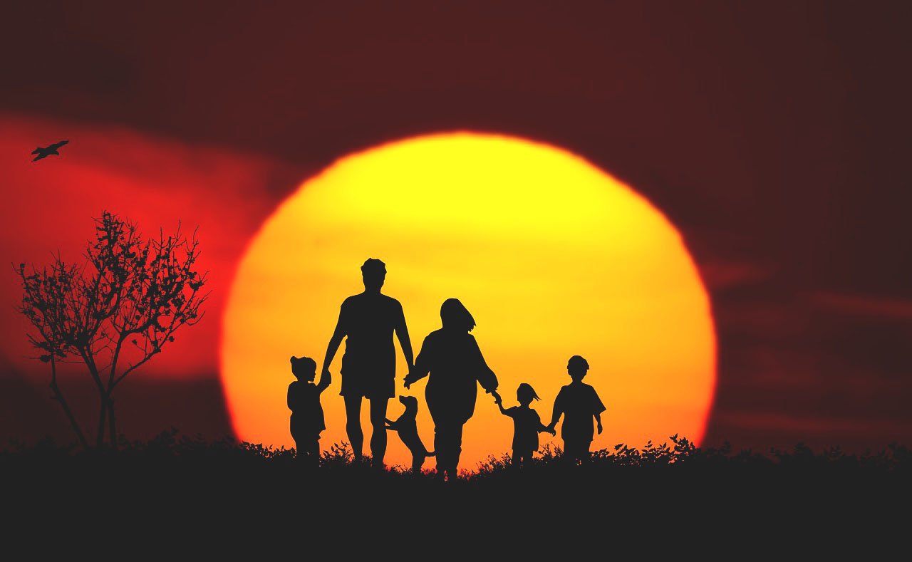 Imagem de uma família passeando na natureza ao pôr do sol com seu cachorro