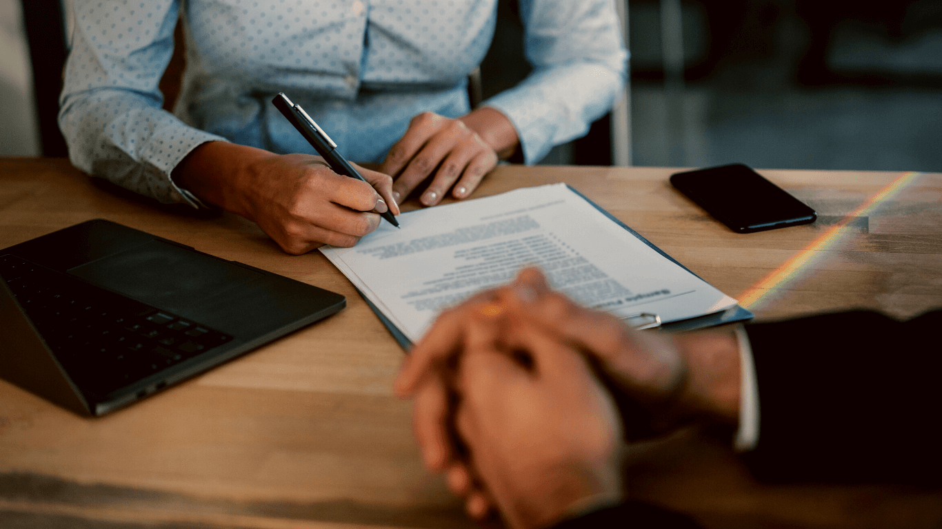 Mulher assinando contrato na frente de um advogado