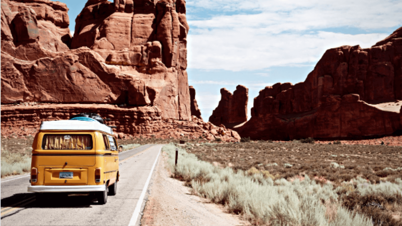 kombi amarela andando em uma estrada no deserto