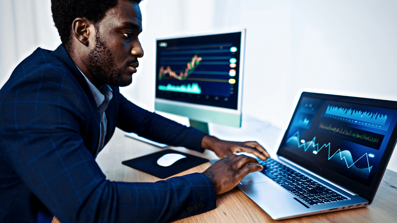 Homem operando criptoativos em dois computadores