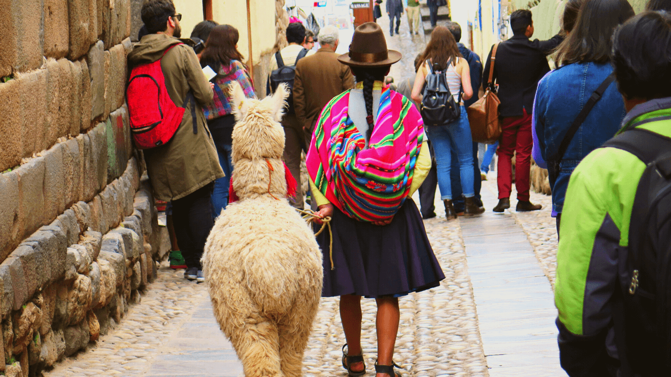 Mulher andando na rua com uma lhama no Peru