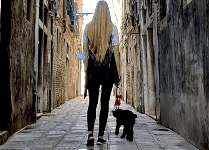 Uma imagem contendo uma mulher viajando pela Europa com seu cachorro