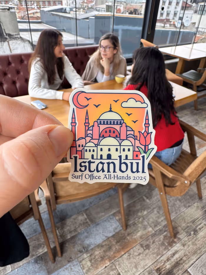 Mano che regge un adesivo con un'illustrazione dei monumenti di Istanbul, una luna crescente e un tulipano, con la scritta 