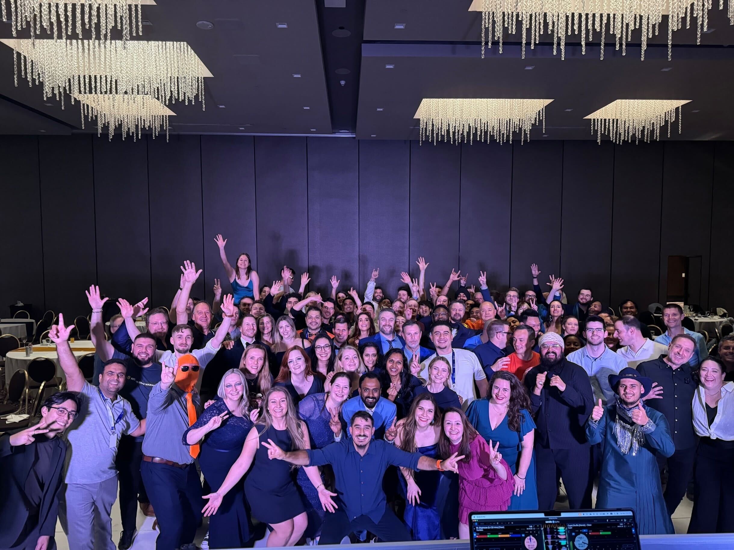 The Secure Code Warrior team in a large hall cheering with their hands in the air