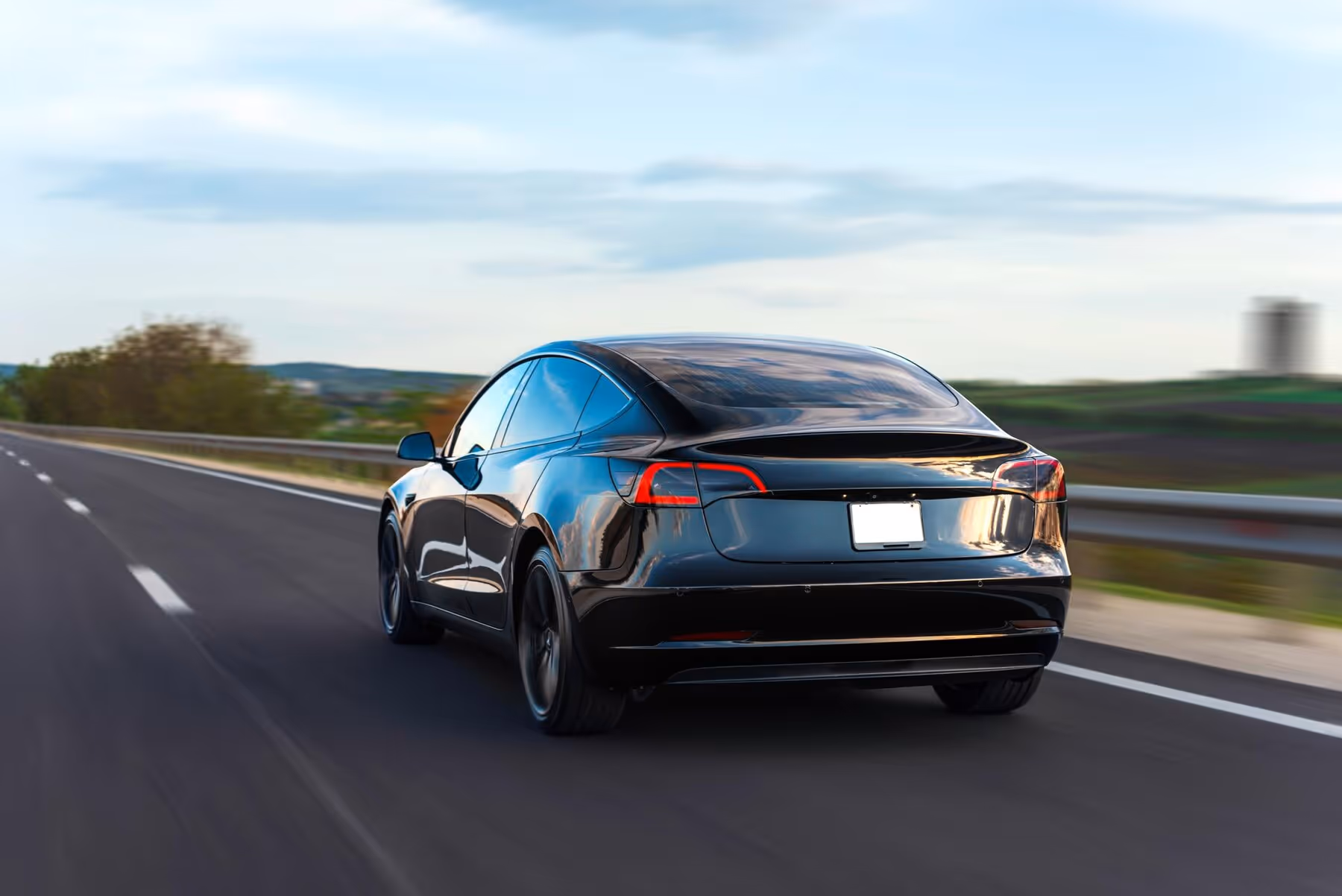 Black car driving on the road, illustrating Tesla dent repair cost