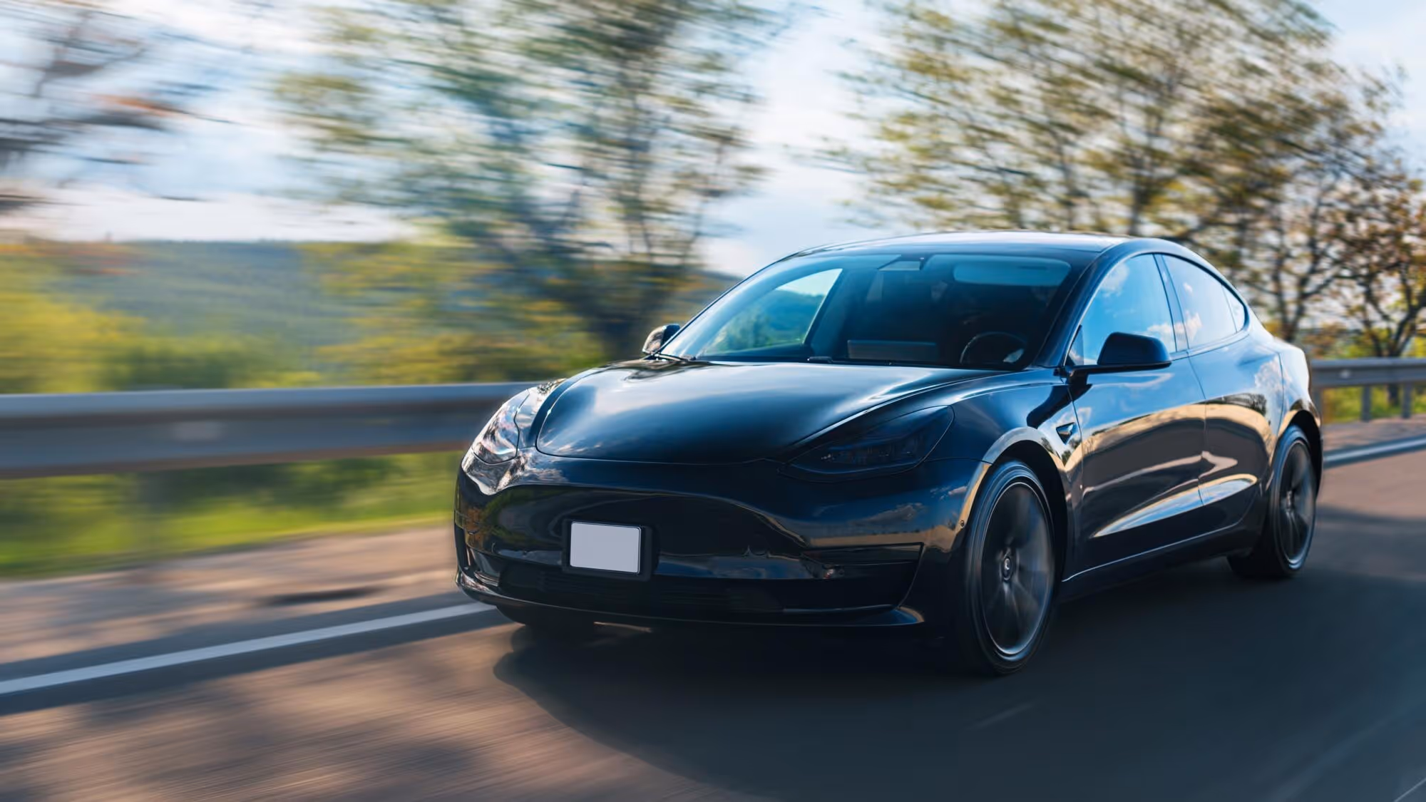 Black car driving on the road, illustrating Tesla side panel replacement cost