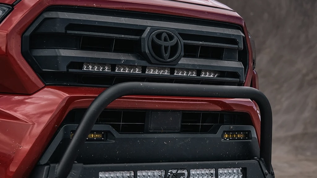 Red Toyota pickup front grille with bull bar and LED light bar