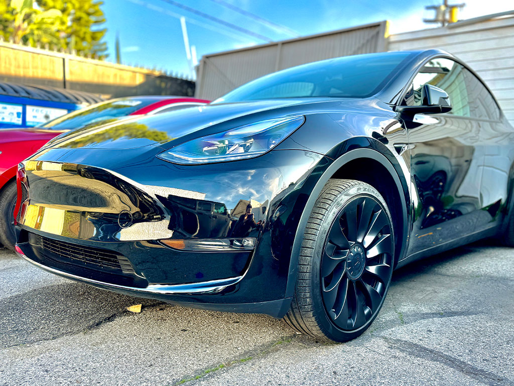 Black Tesla Model Y with front bumper collision damage