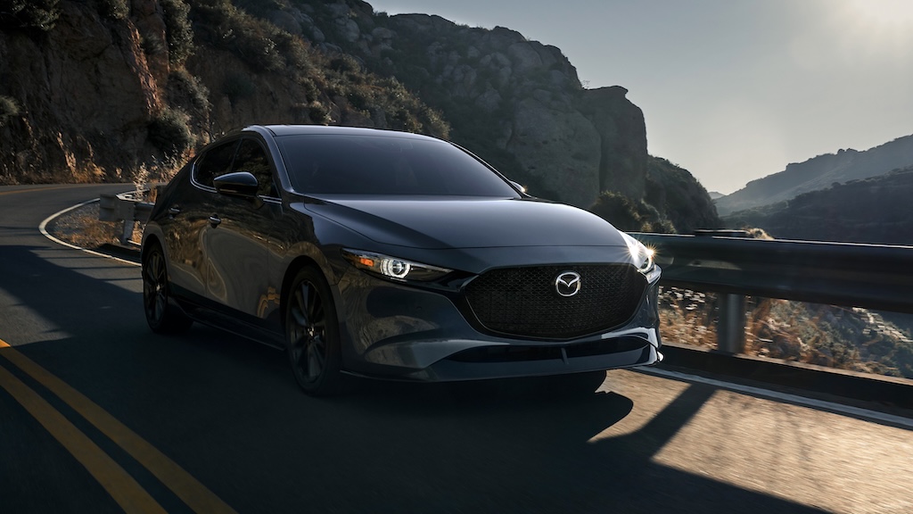 Dark gray Mazda3 hatchback on a winding mountain road