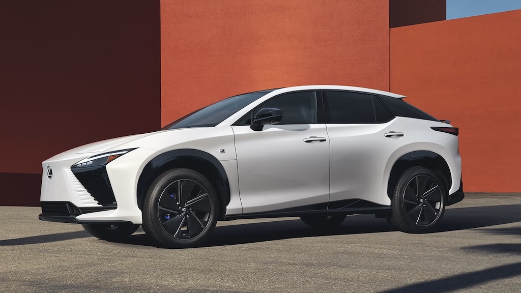 White Lexus RZ electric SUV parked beside a red wall