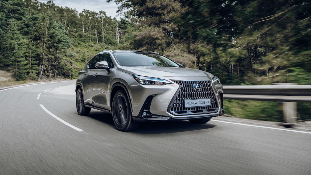 Silver Lexus NX crossover driving on a forest road